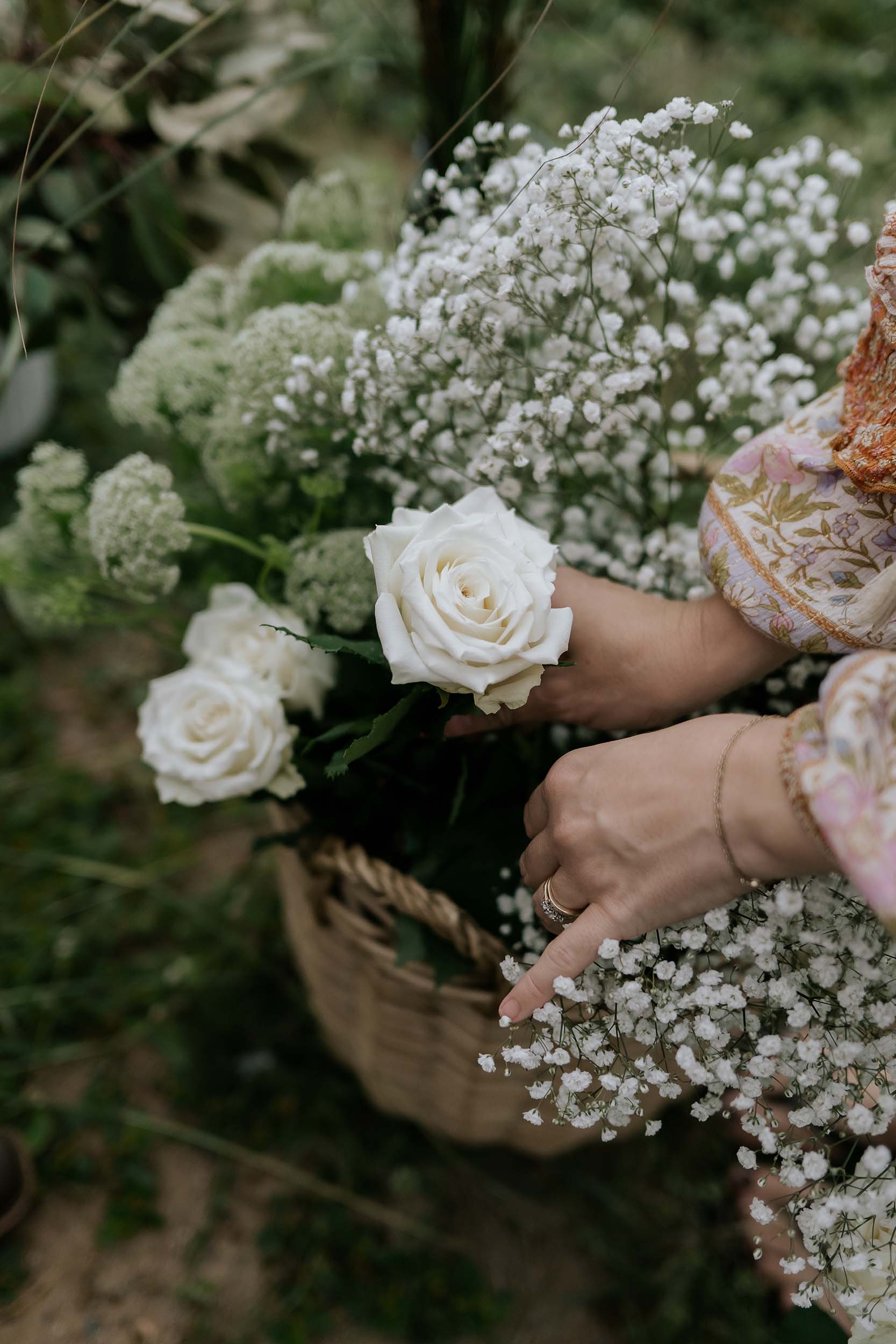 Person holding a bouquet of white flowers with a blurred natural background